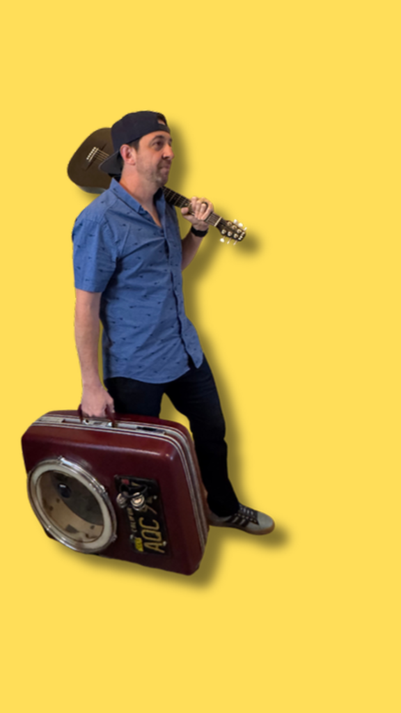 Sean Eddy press photo: Fort Worth one-man band with guitar and vintage suitcase drum on a yellow background